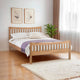 Wooden bed with white bedding and a purple blanket in a bedroom setting.