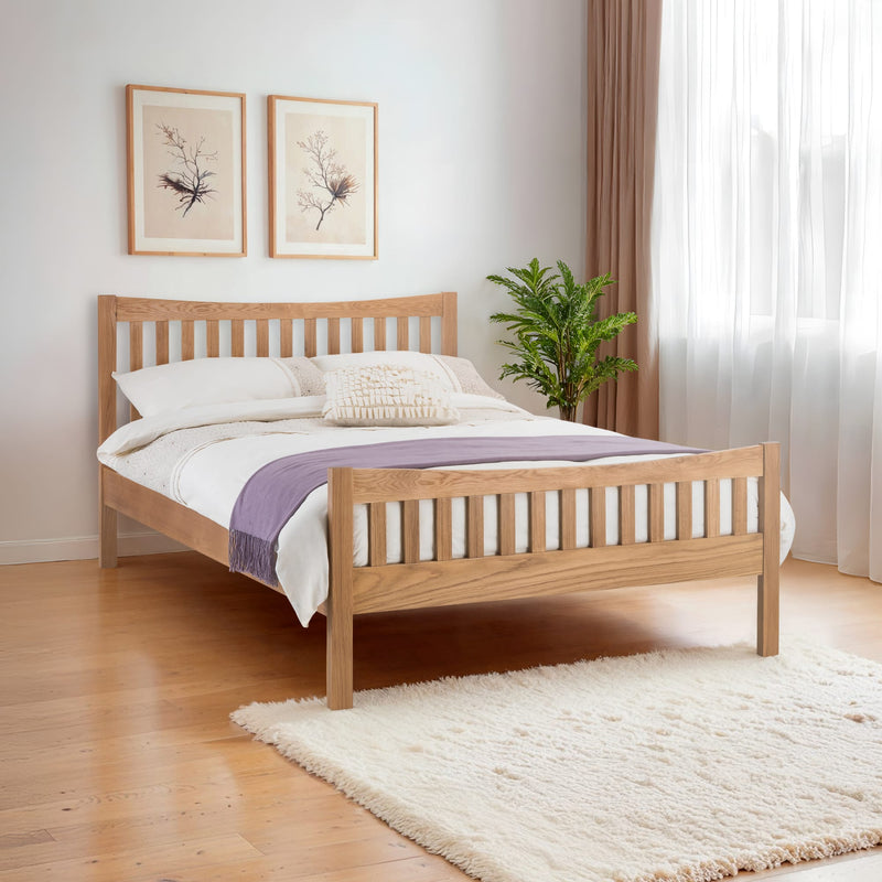 Wooden bed with white bedding and a purple blanket in a bedroom setting.