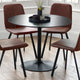 Round black dining table with four brown chairs in a room with large windows.