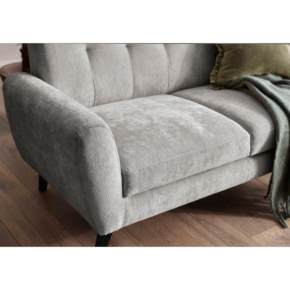Gray sofa with a green pillow and blanket on a wooden floor