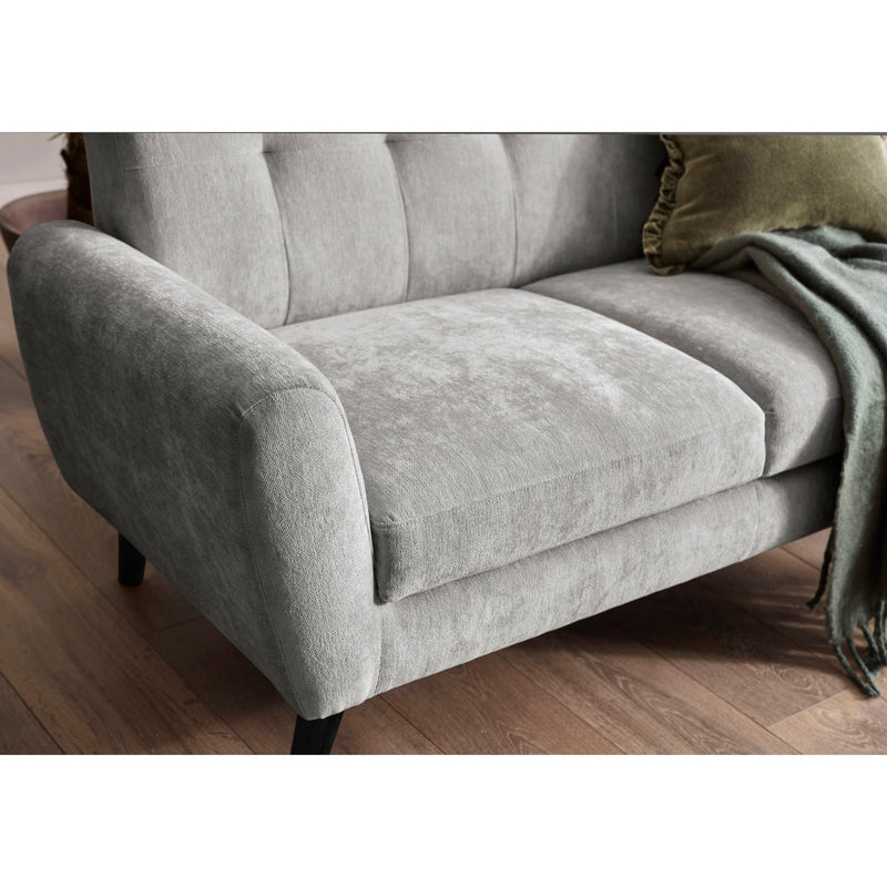 Gray sofa with a green pillow and blanket on a wooden floor