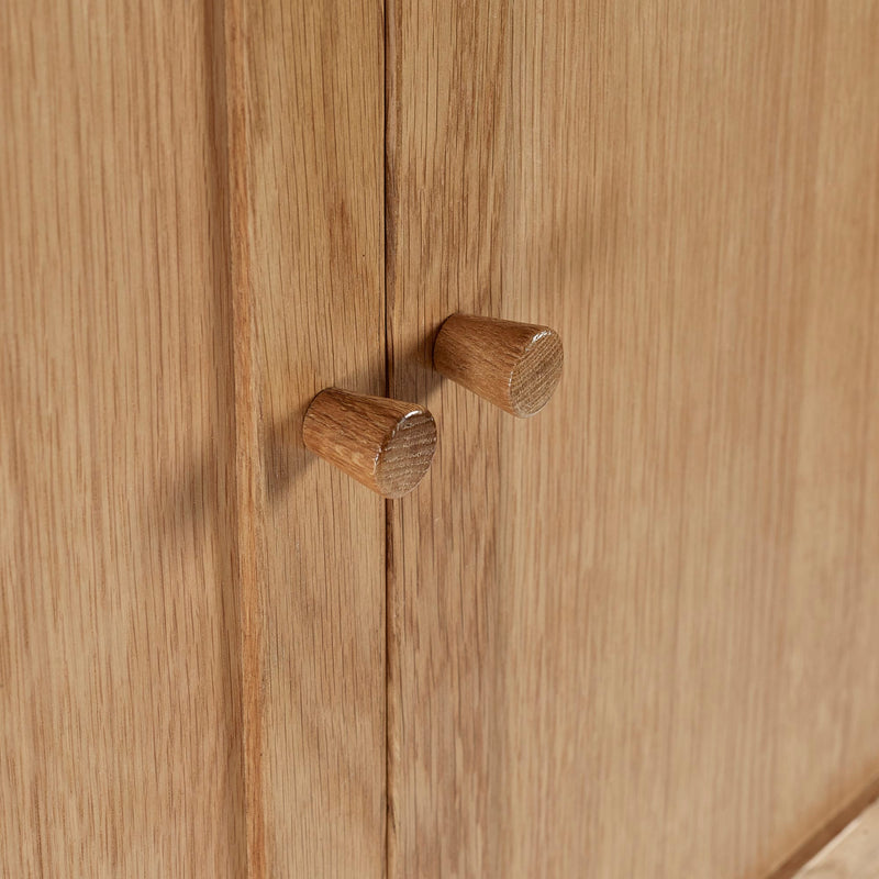 Close-up of wooden cabinet doors with round knobs on a wooden surface.