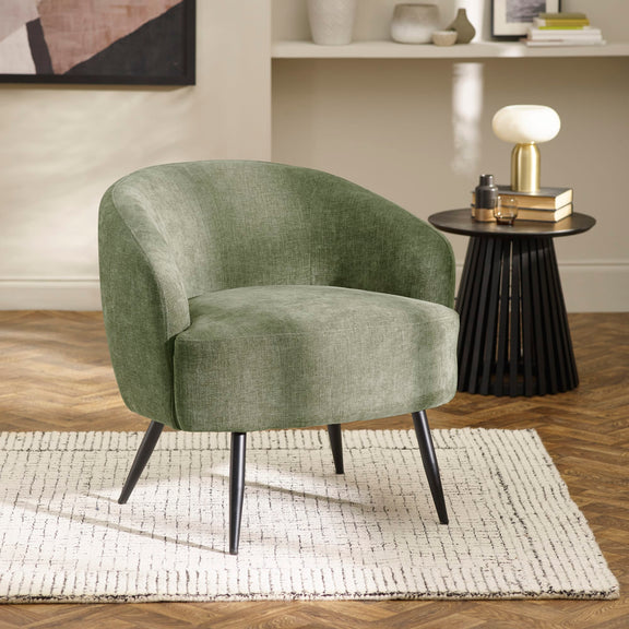 Green armchair in a room with a side table and decor items.
