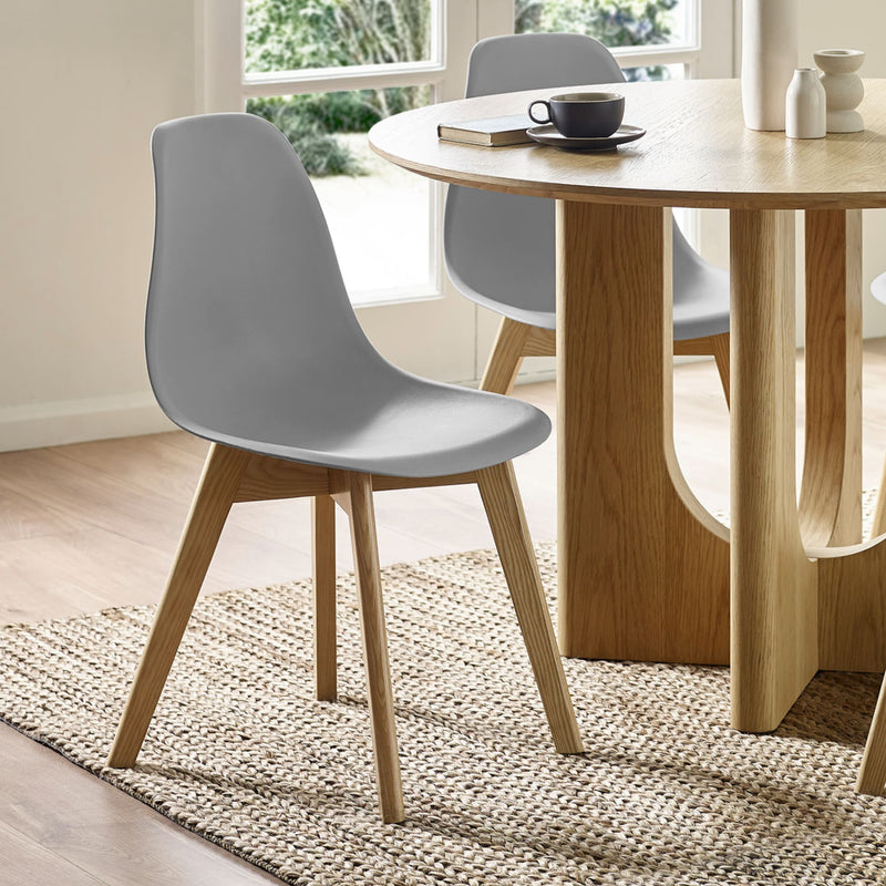 Dining room with wooden table and gray chairs on a light wood floor.