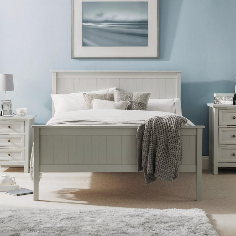 Neatly made bed in a bedroom with light blue walls, nightstands, and a painting.