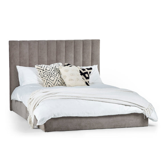 Gray upholstered bed with white bedding and decorative pillows on a white background