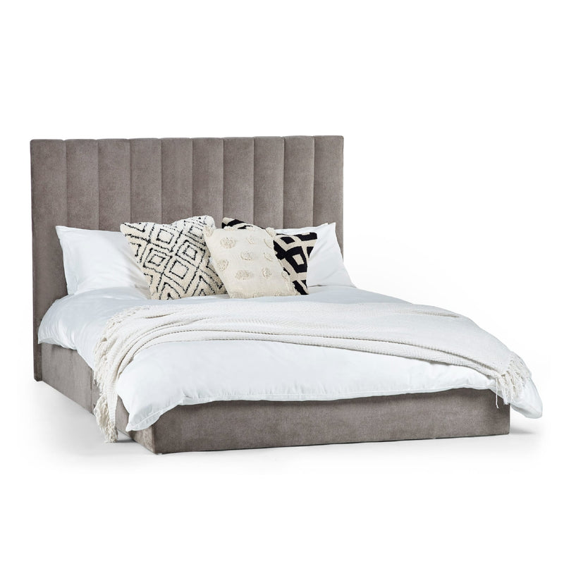 Gray upholstered bed with white bedding and decorative pillows on a white background