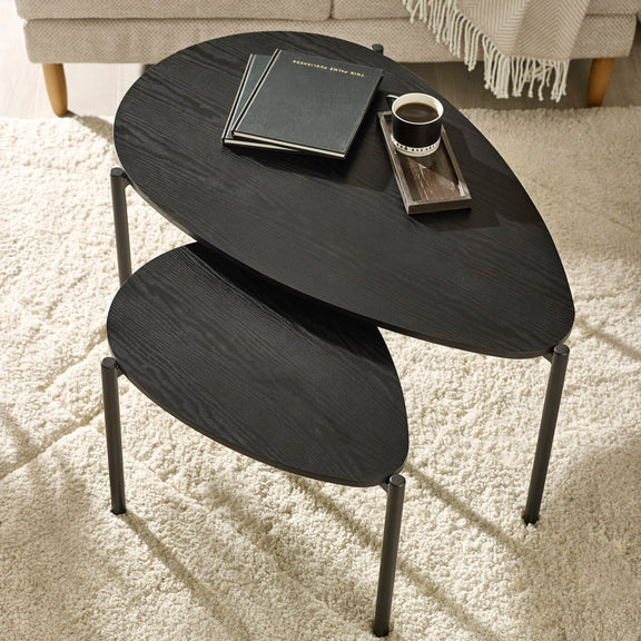 Black nesting tables with a cup and books on a light carpet