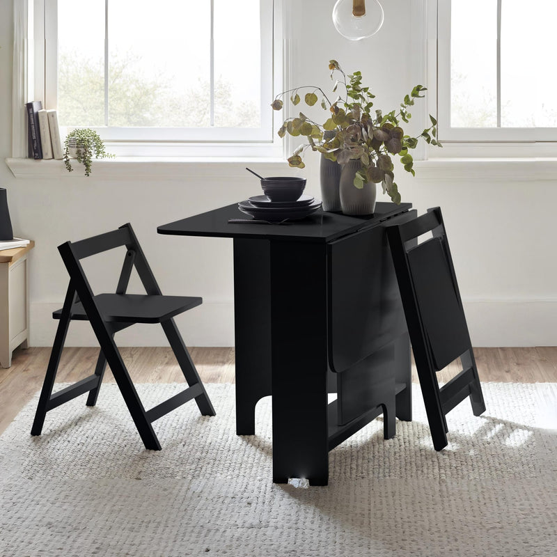 Black dining table with chairs in a bright room with large windows.