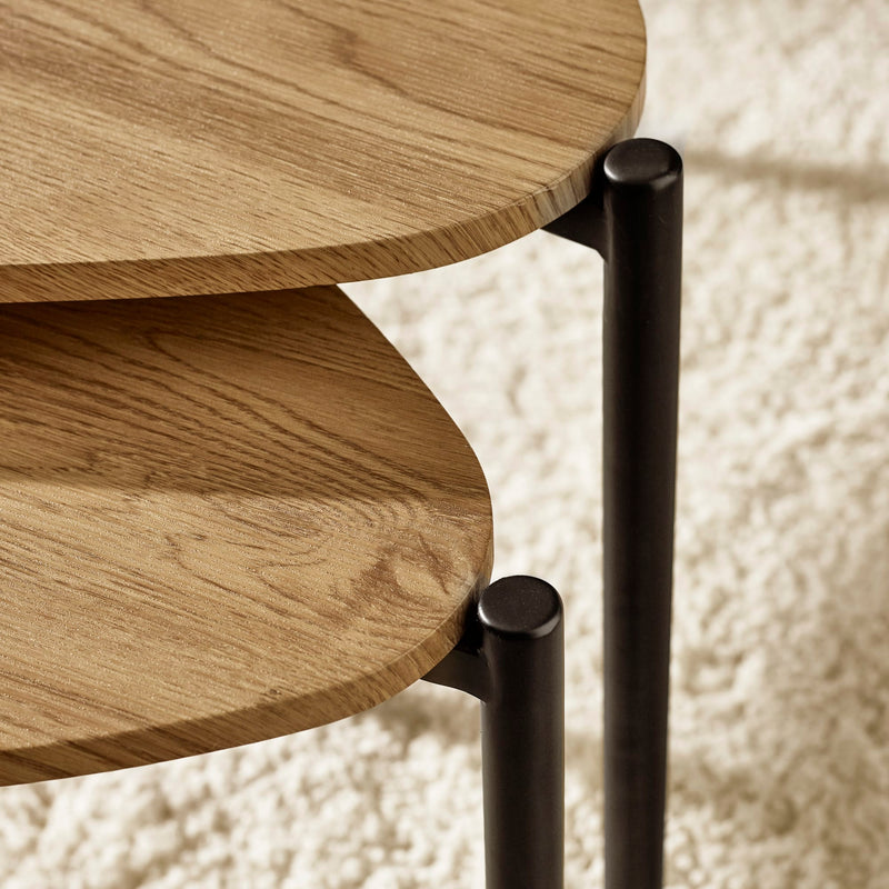 Close-up of a wooden side table with black metal legs on a textured white background