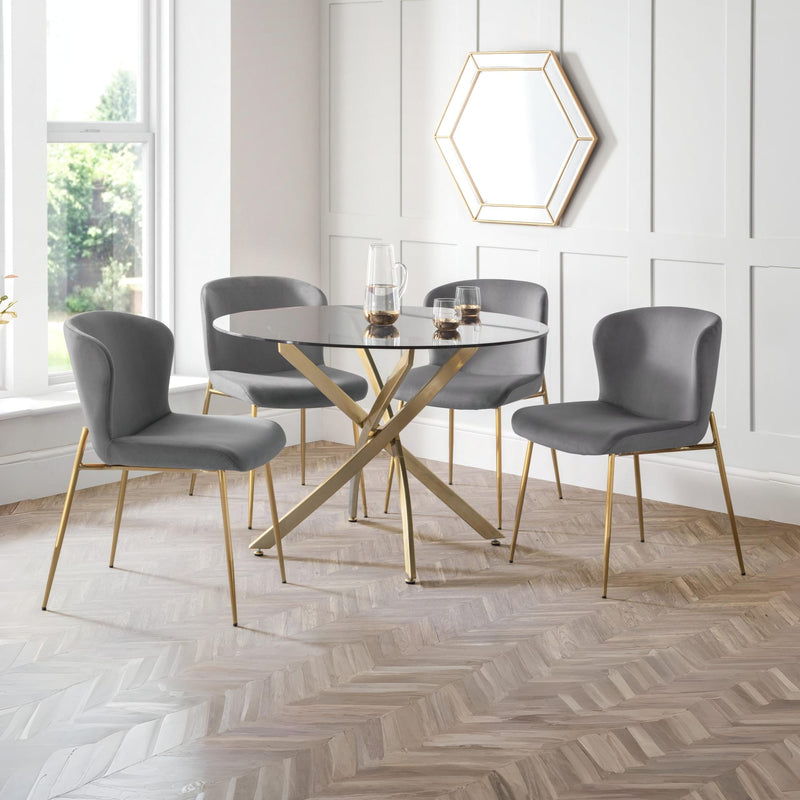 Dining room with a round glass table and four gray chairs on a wooden floor.