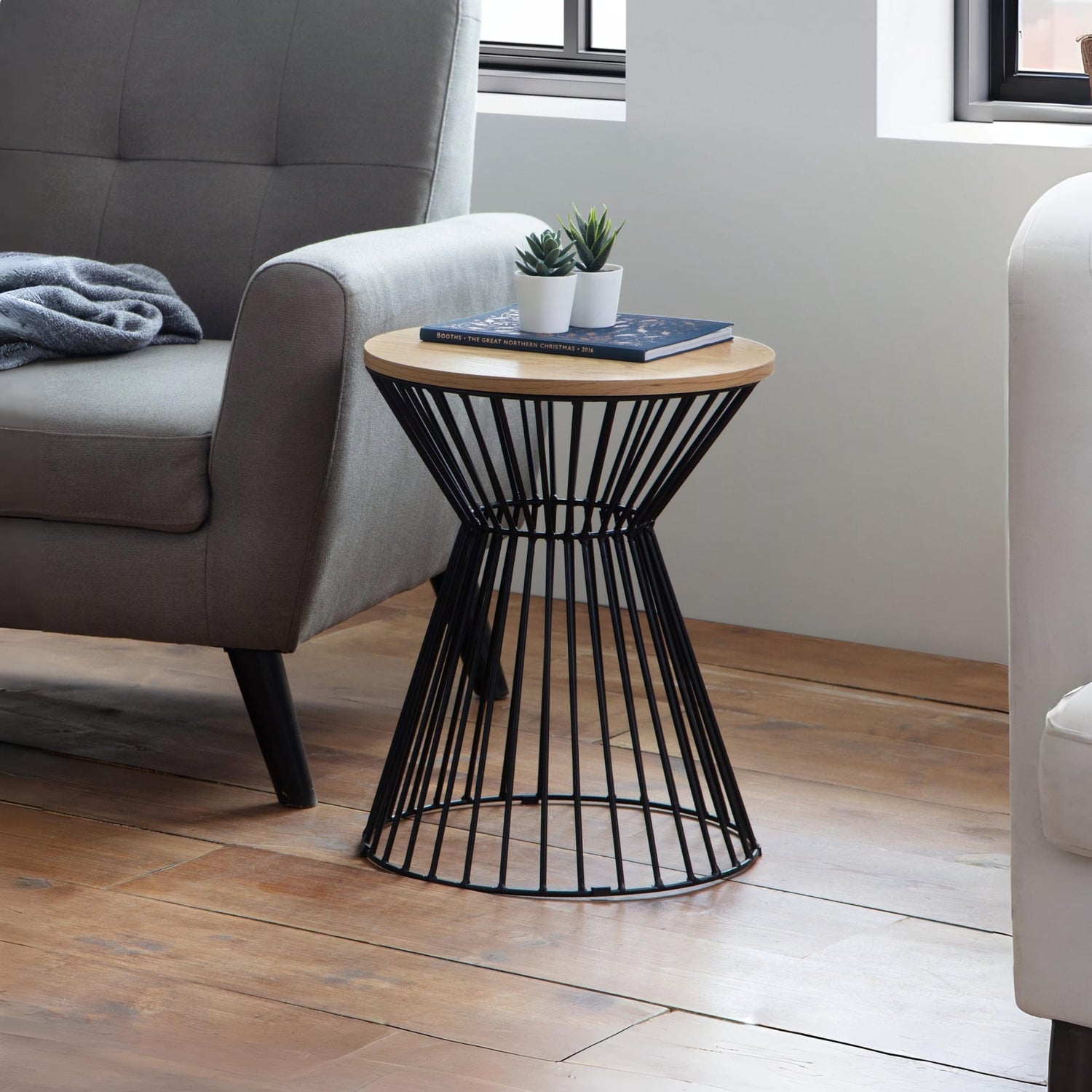 Modern side table with black metal base and wooden top in a living room setting.
