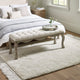 Bedroom with a tufted bench, bed, and rug.