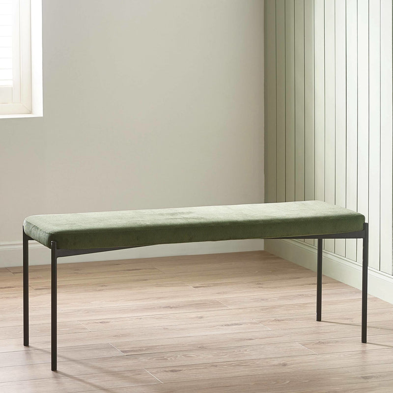 Green upholstered bench with black metal legs on a wooden floor.