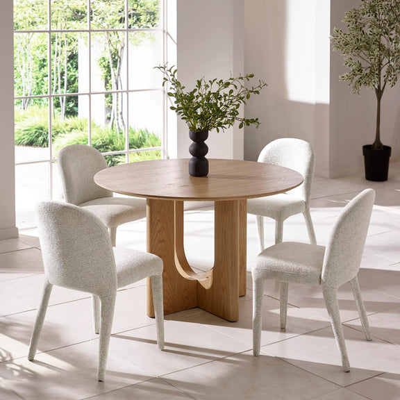 Dining room with a round wooden table and four white chairs.