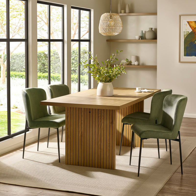 Dining room with wooden table and green chairs near large windows.