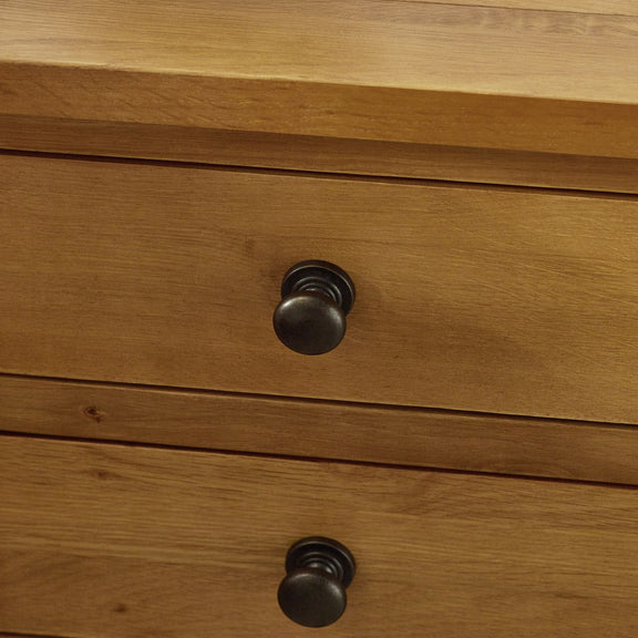 Wooden drawer with black knobs on a wooden surface
