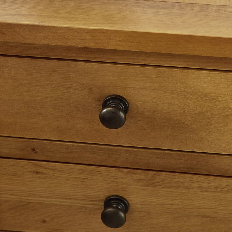 Wooden drawer with black knobs on a wooden surface