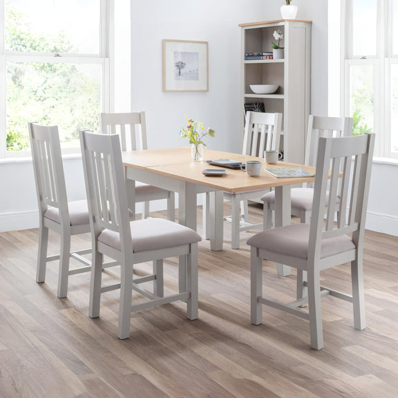 Dining room with a wooden table and gray chairs in a well-lit room.