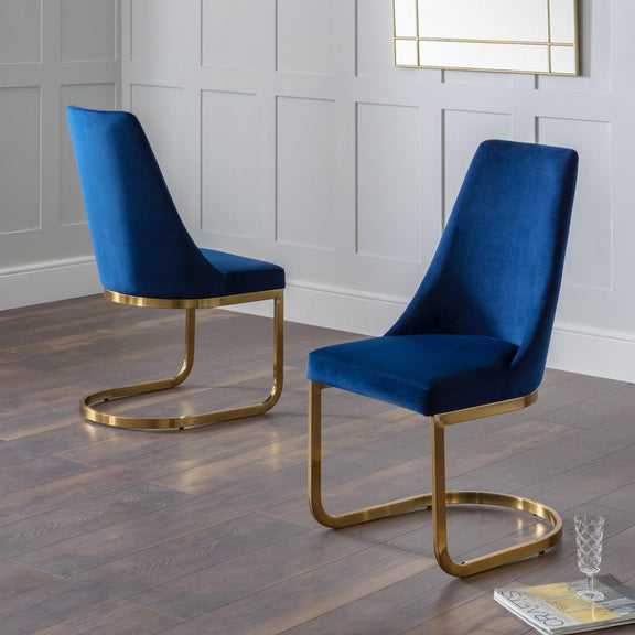 Two blue velvet chairs with gold frames on a wooden floor.