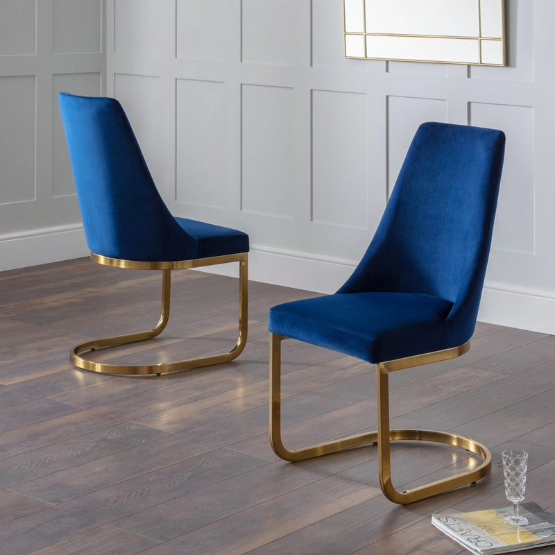 Two blue velvet chairs with gold frames on a wooden floor.