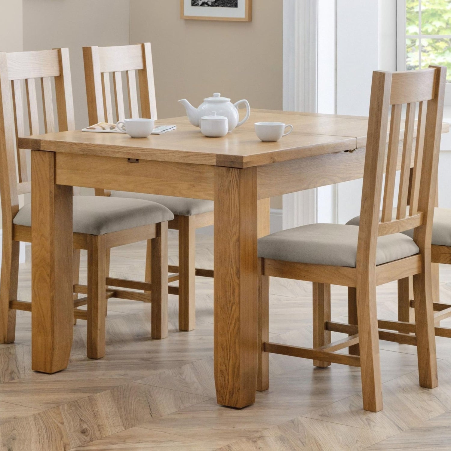 Wooden dining table with chairs and a teapot on a wooden floor.