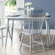 Dining table set with chairs in a room with a blue wall and window.