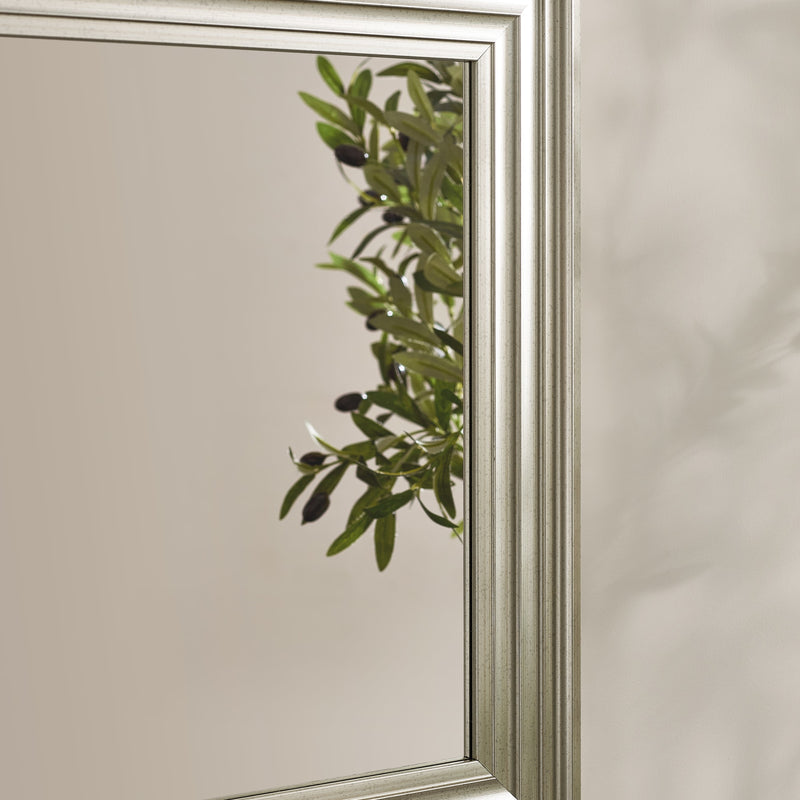 Decorative mirror with olive branch design on a neutral background