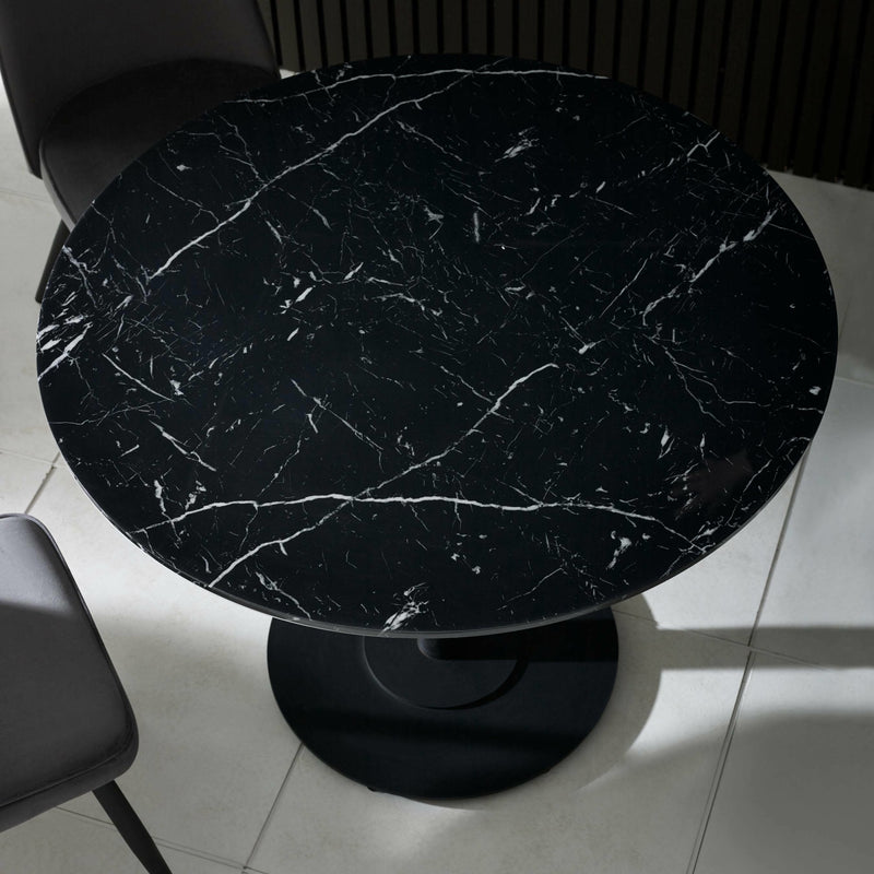 Round black marble table with a white floor and chair in the background