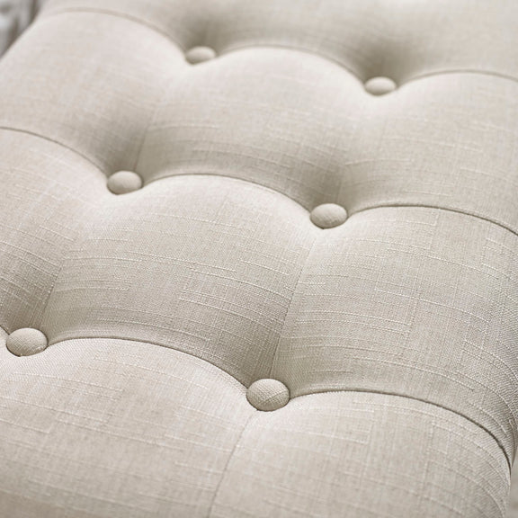 Close-up of a tufted beige fabric surface with button details