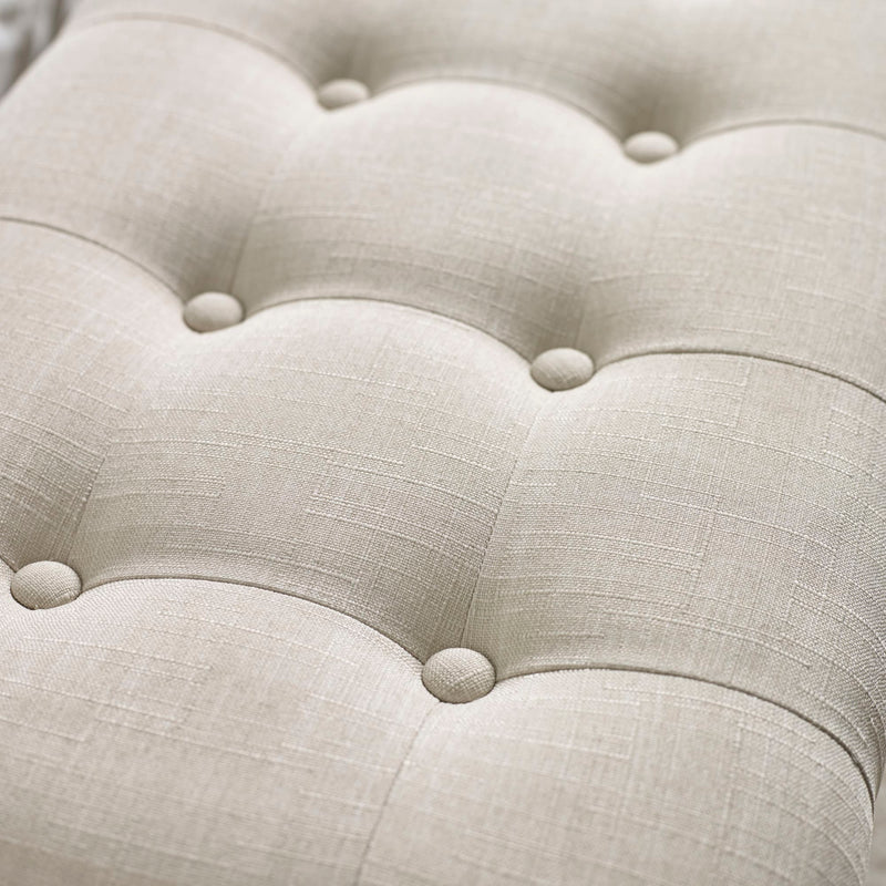 Close-up of a tufted beige fabric surface with button details
