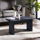Black coffee table in a living room with a gray sofa and decorative items.