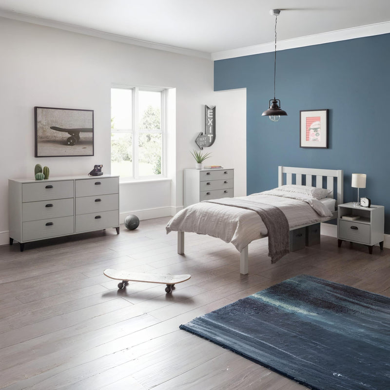 Modern bedroom with a blue accent wall, bed, dresser, and rug.