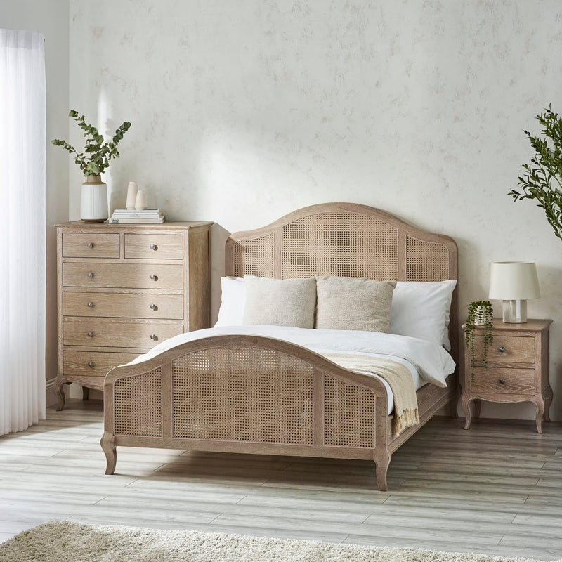 Bedroom with wooden bed, nightstands, and dresser against a light wall.