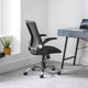 Black office chair in front of a desk with a laptop in a minimalistic room.