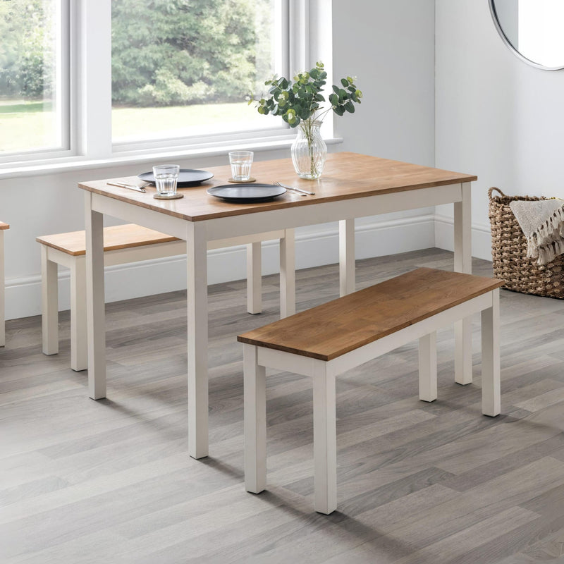 Dining table set with benches in a room with large windows.