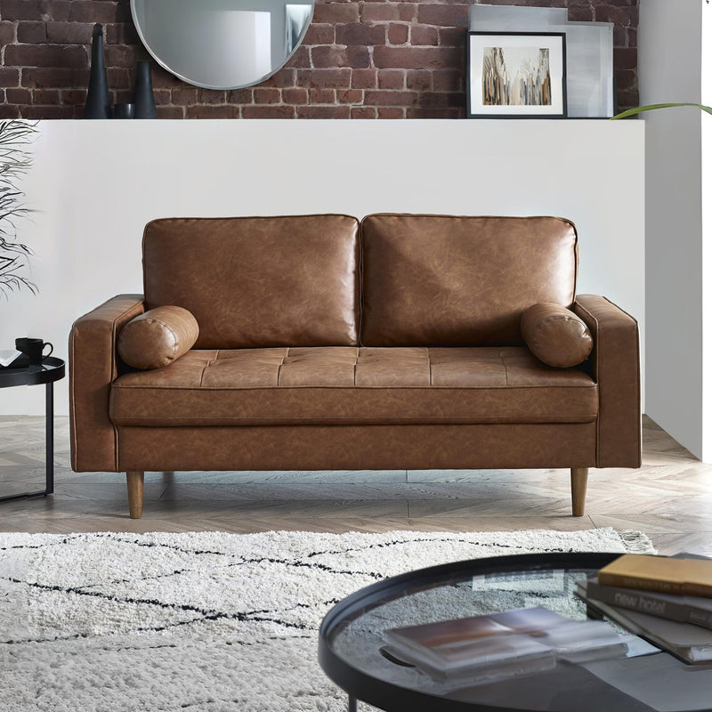 Brown leather sofa in a living room setting with a coffee table and rug.