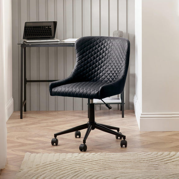 Black quilted office chair in a room with a desk and laptop.
