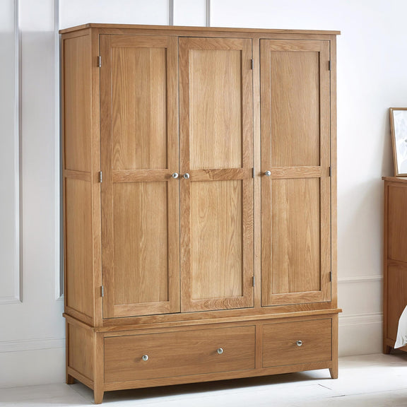 Wooden wardrobe with four doors and two drawers in a room setting.