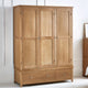 Wooden wardrobe with four doors and two drawers in a room setting.