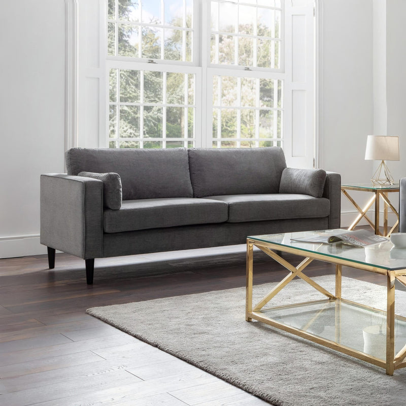 Gray sofa in a modern living room with a glass coffee table and lamp.