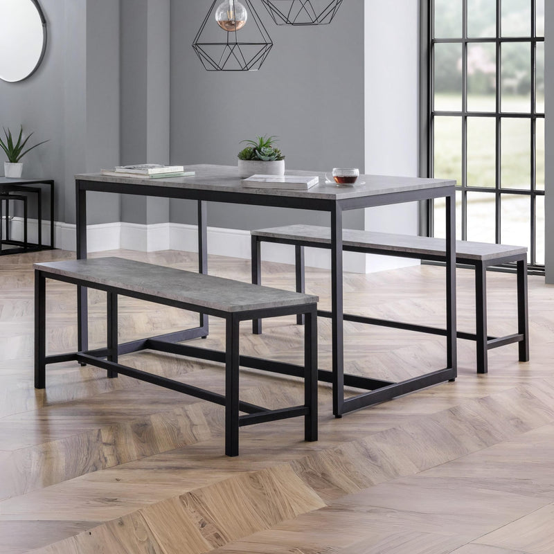 Dining table set with benches in a modern room with large windows.