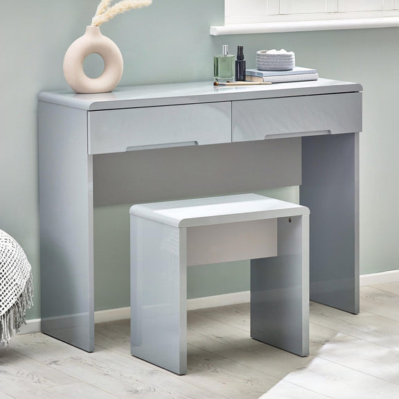 Gray vanity table with a smaller matching stool against a light gray wall.
