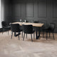Dining area with a wooden table and black chairs against a dark paneled wall.