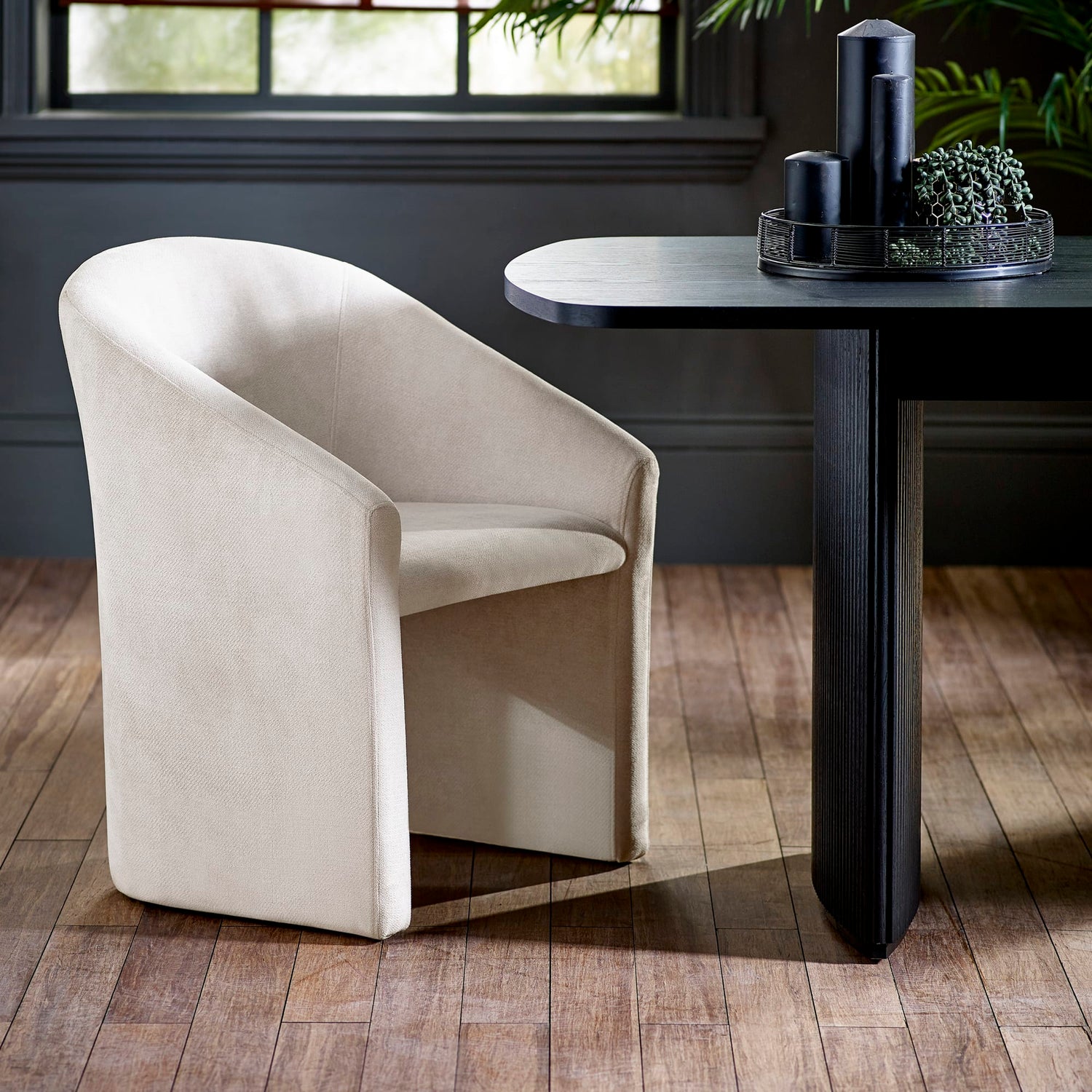 Beige armchair in a room with a black table and decorative items.