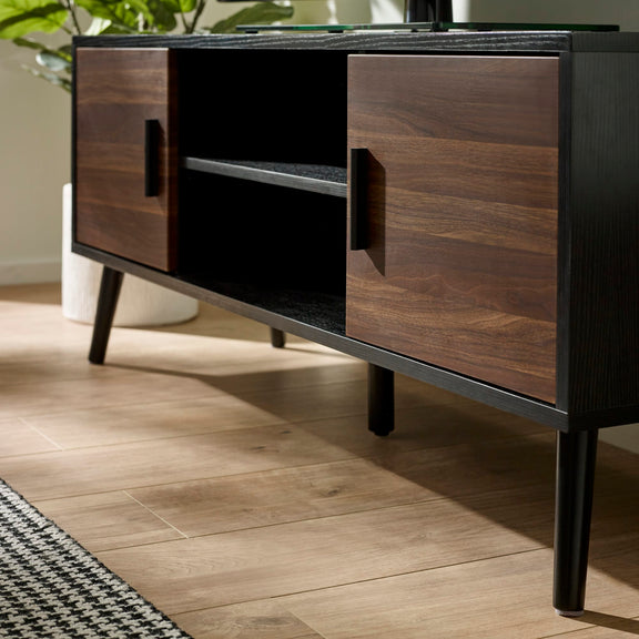 Wooden entertainment console with black accents on a wooden floor.