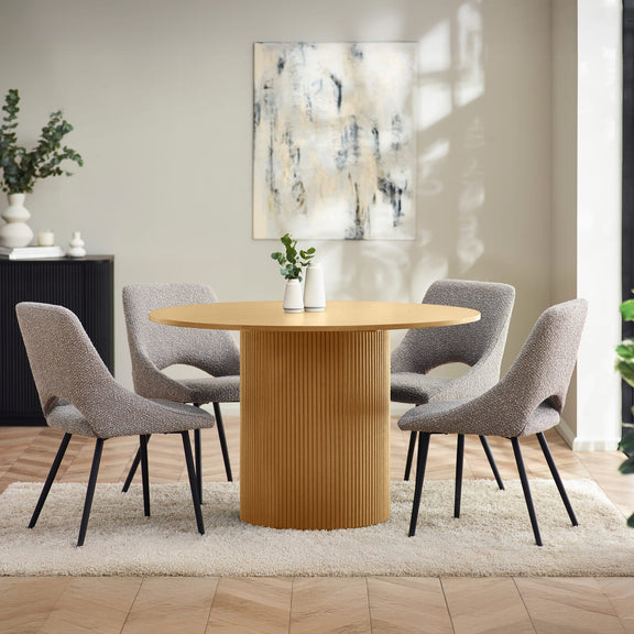 Dining room with a round wooden table and gray chairs, featuring a abstract painting on the wall.