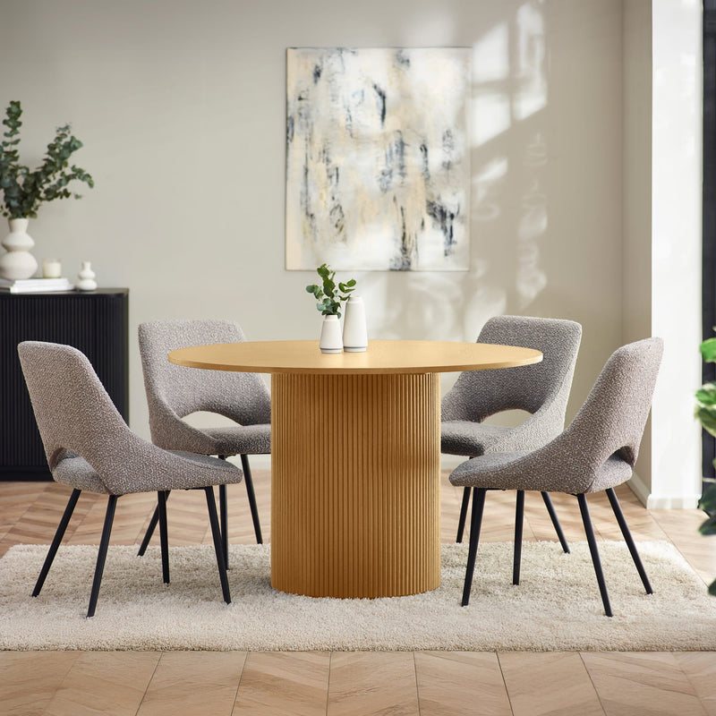 Dining room with a round wooden table and gray chairs, featuring a abstract painting on the wall.