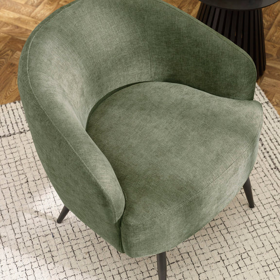Green armchair on a textured rug with a wooden floor background