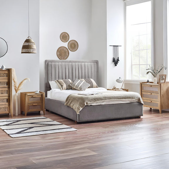 Modern bedroom with a gray upholstered bed, wooden nightstands, and decorative elements.